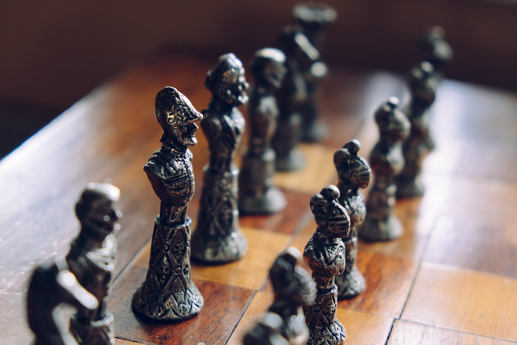 Ornate metal chess pieces on a wooden board